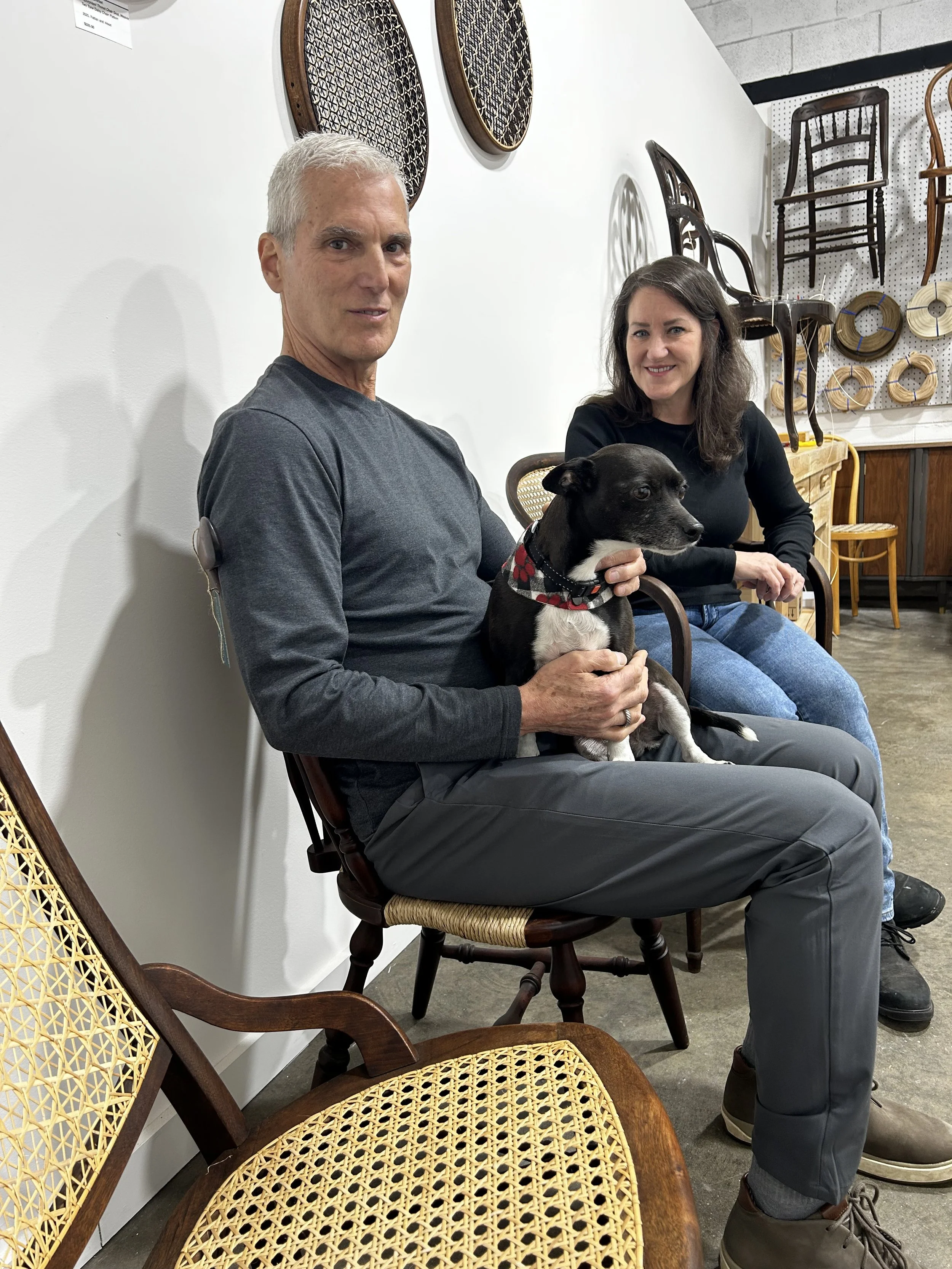 Mitch and Deb of Friend of Furniture in their open to the public, Asheville River Arts District studio surrounded by chairs with hand-woven seats.