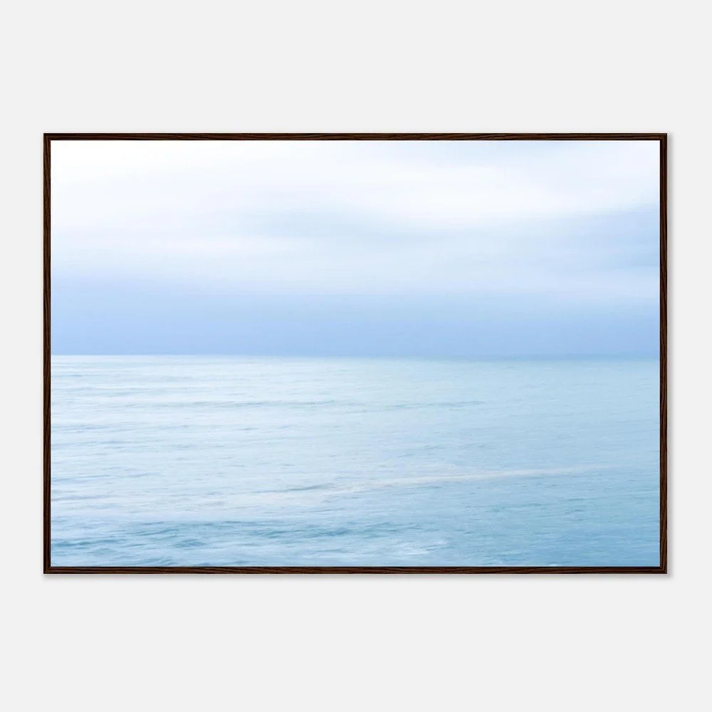 Framed photograph of a calm ocean with cloudy sky above.