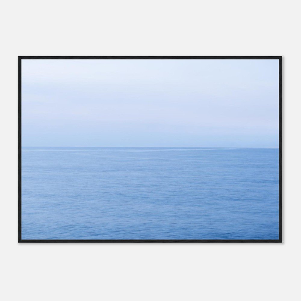 A framed photograph of a calm blue ocean with a light blue sky above.