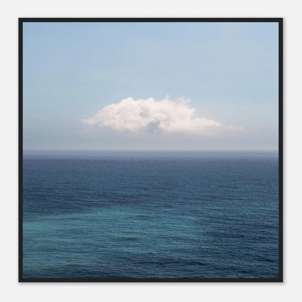 An ocean view with calm blue water under a clear sky and a single white cloud.