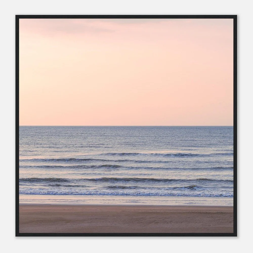 A framed photograph of a peaceful ocean scene at sunset, with gentle waves and a pinkish sky.