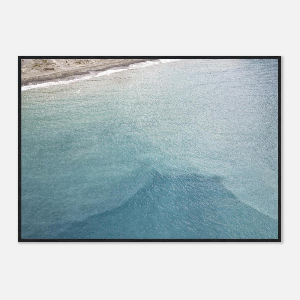 Frame of a framed aerial view of the ocean with a shoreline in the top left corner.