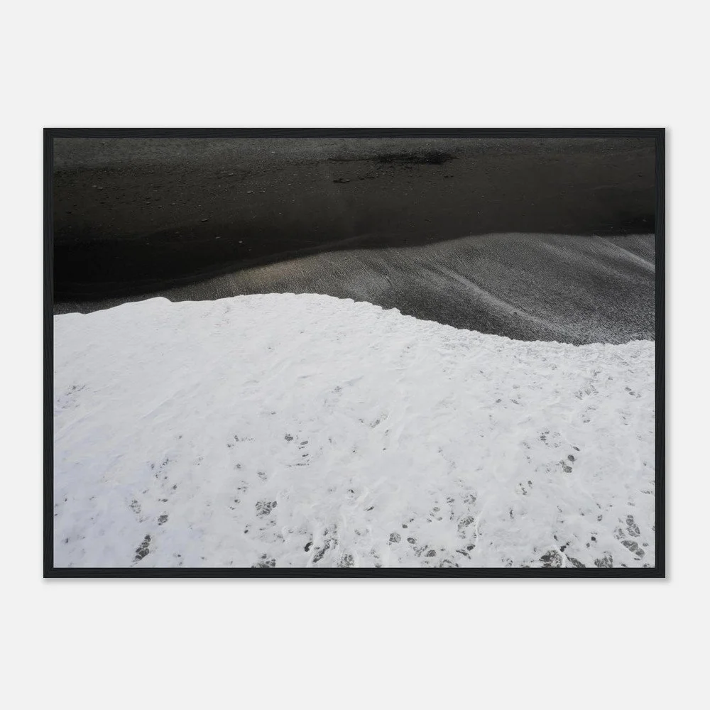 A framed black and white landscape photograph of snow on the ground with dark mountains or hills in the background.