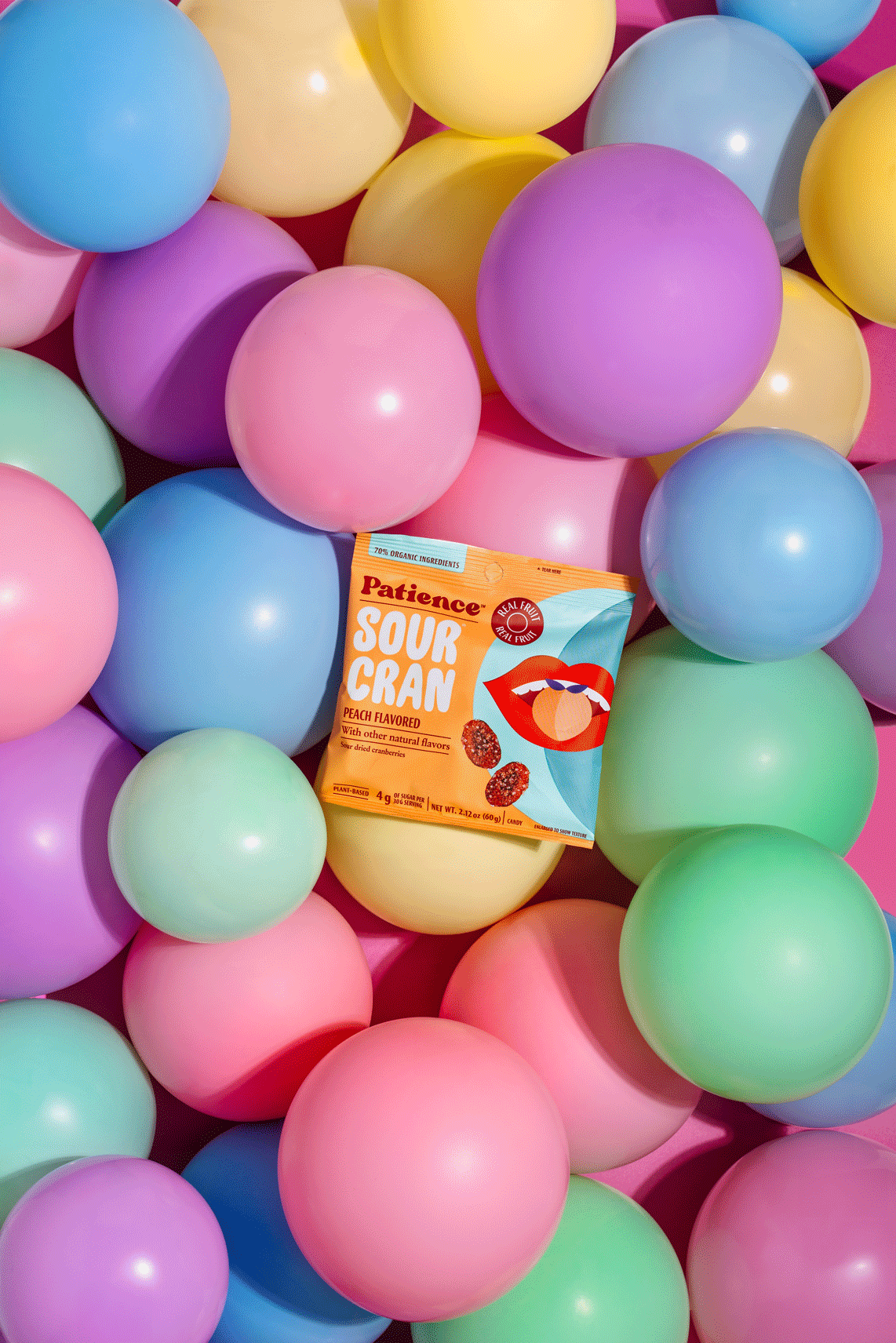Colorful pastel plastic balls with a package of Peach Flavored Sour Cran candy placed among them.