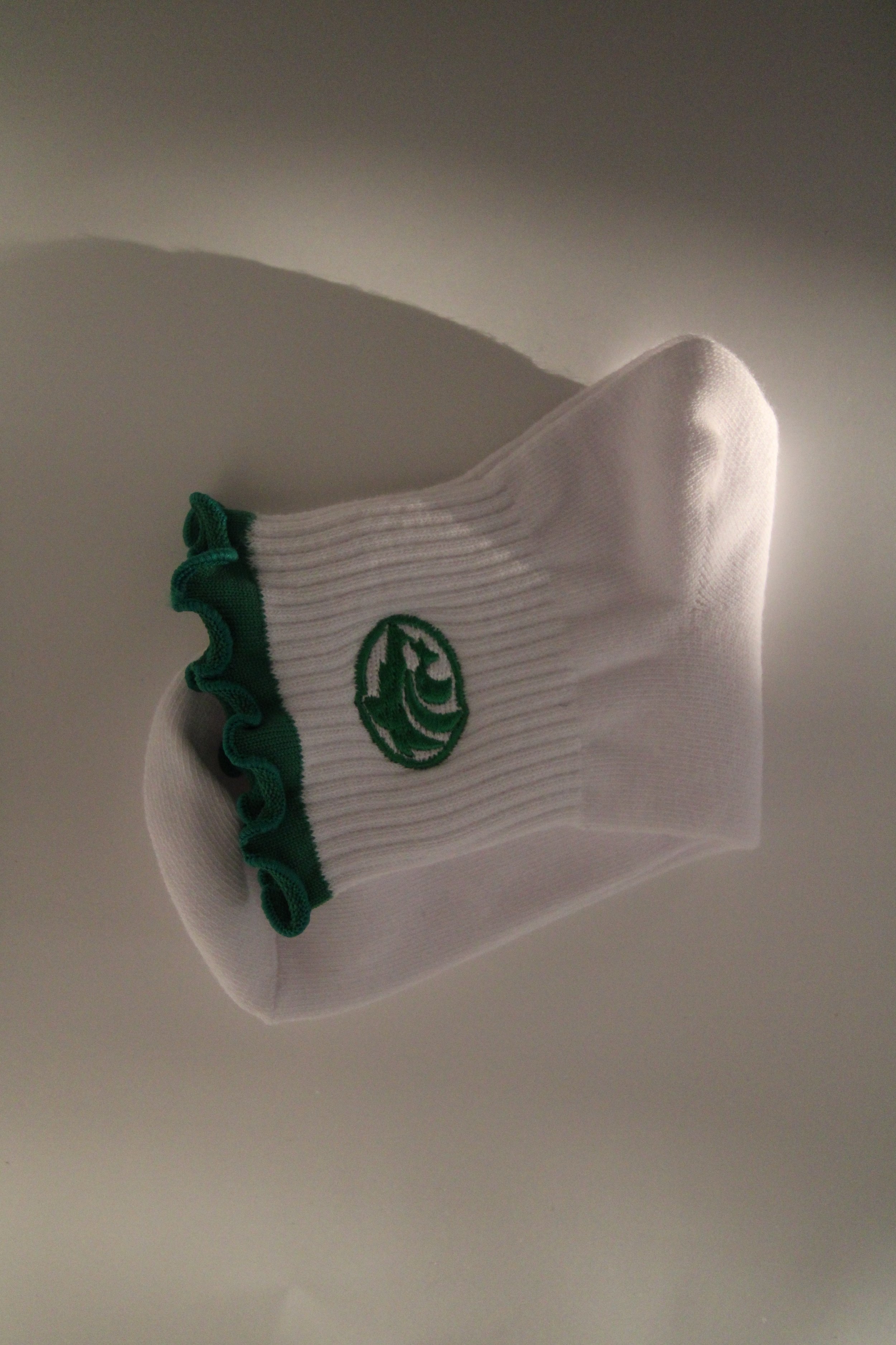 White sock with green accents and a Buford Wolf logo, hanging against a plain background.