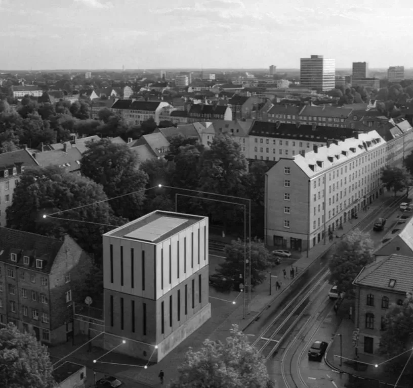 Schwarz-weiß Foto einer modernen vierstöckigen Gebäudestruktur in einer städtischen Umgebung, mit Tramlinien, Straßen und älteren Gebäuden im Hintergrund.