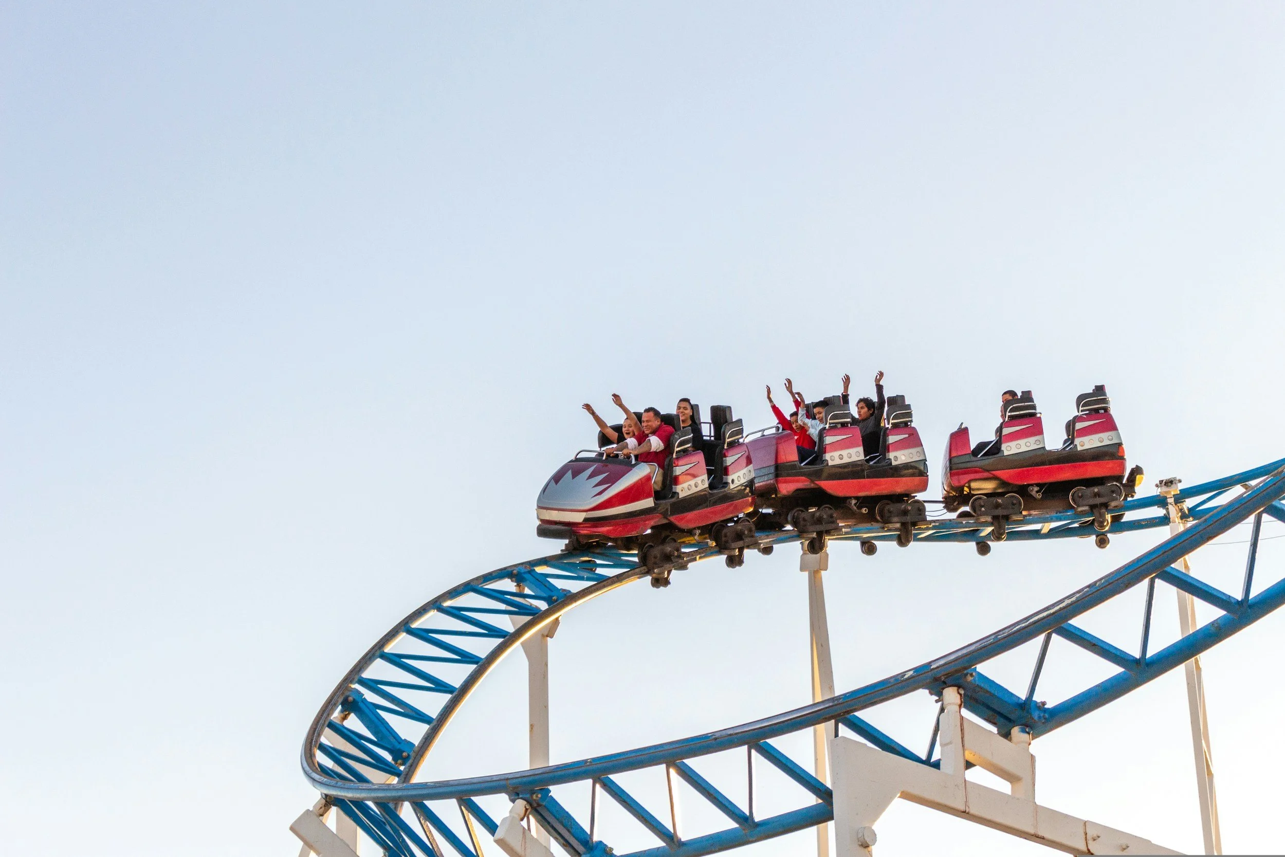 People enjoying a roller coaster ride during daytime at an amusement park.
