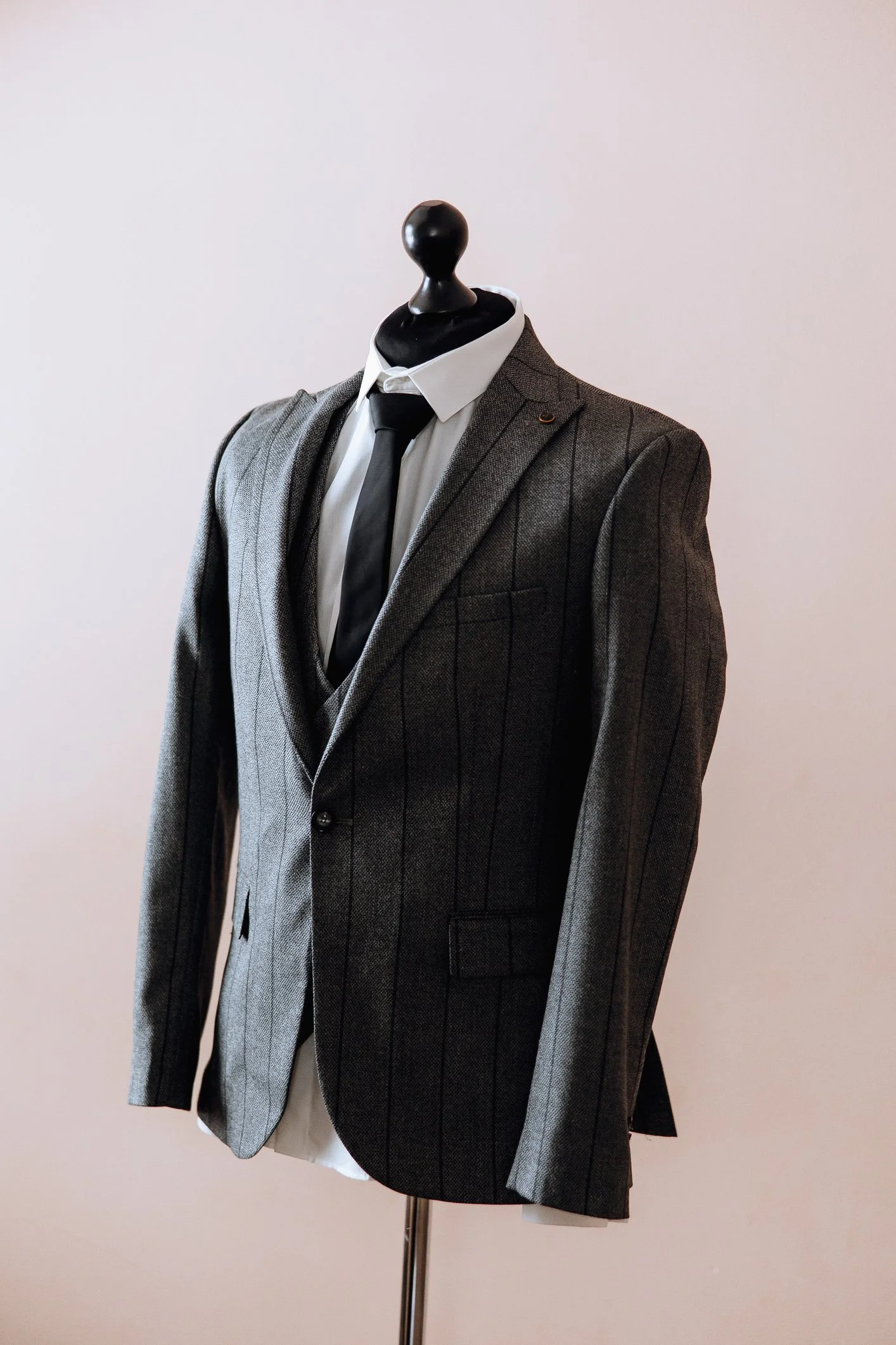 Gray pinstripe suit with white shirt and black tie on a mannequin.