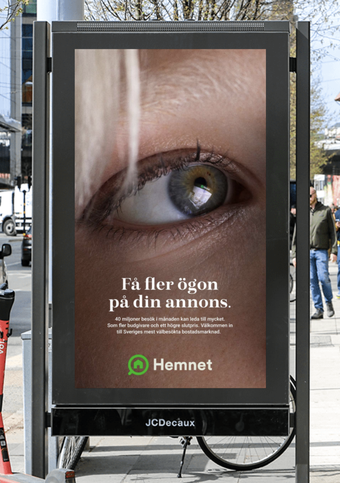Billboard with a close-up of a human eye and text in Swedish about advertising on the eye, with the word 'Hemnet' and a green house logo at the bottom.