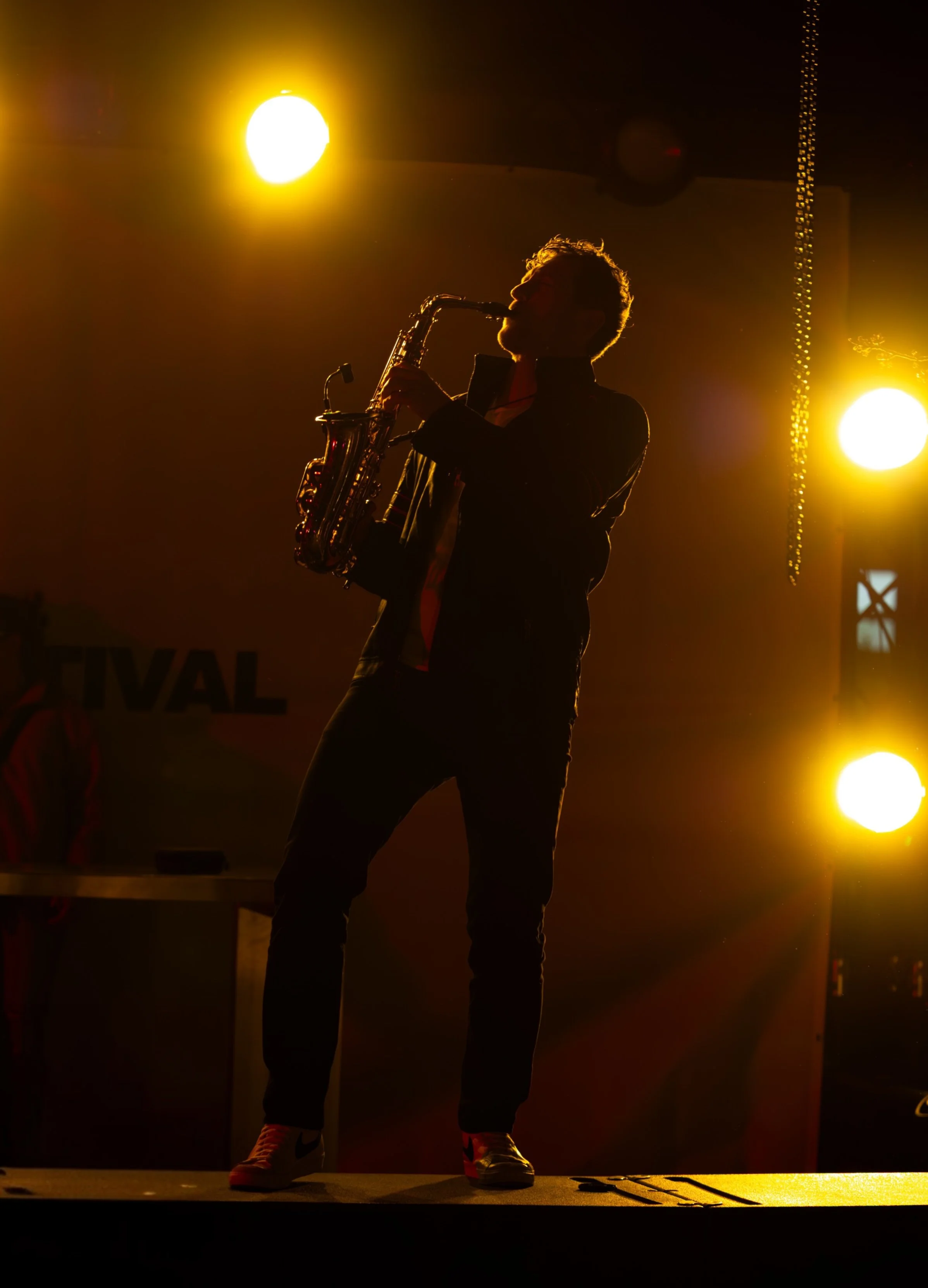 Frederik Heckel spielt auf der Bühne, im Hintergrund sind gelbe Scheinwerfer, der Musiker ist eine Silhouette.