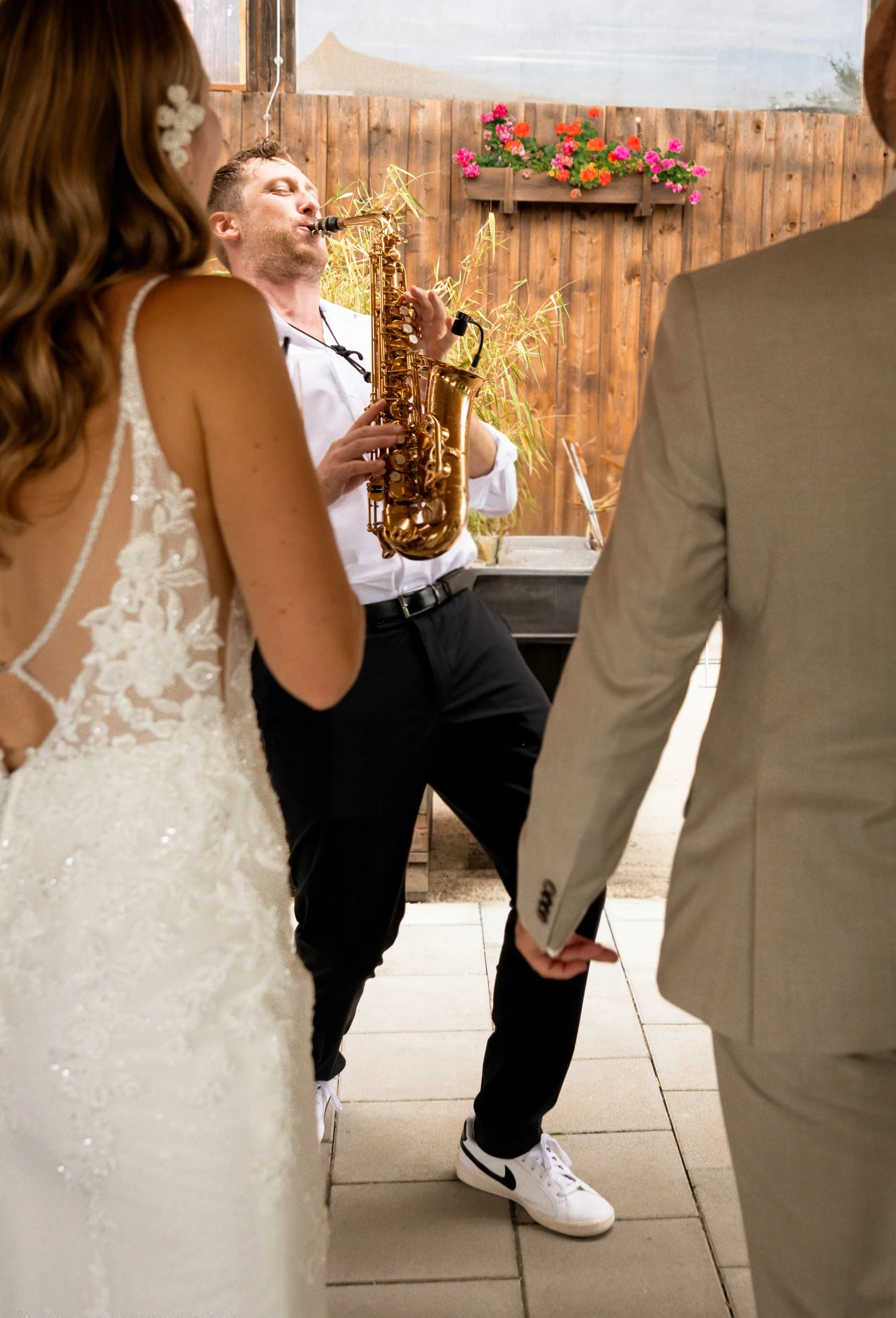 Frederik Heckel spielt Saxophon bei einer Hochzeit, umgeben von Braut und Bräutigam.