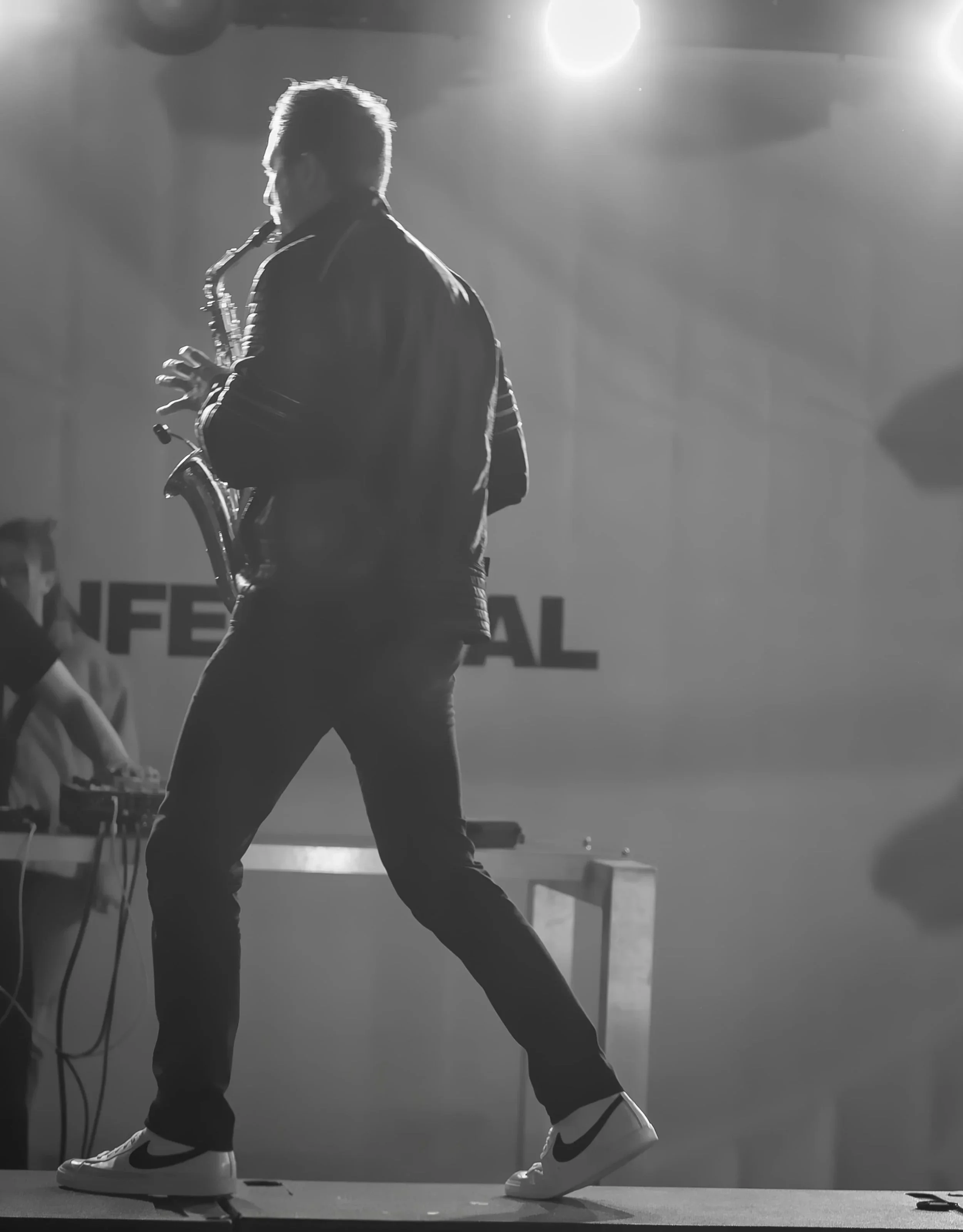 Frederik Heckel spielt Saxophon auf einer Bühne beim Festival, beleuchtet von Scheinwerfern, im Hintergrund ist das Wort »FESTIVAL« sichtbar.