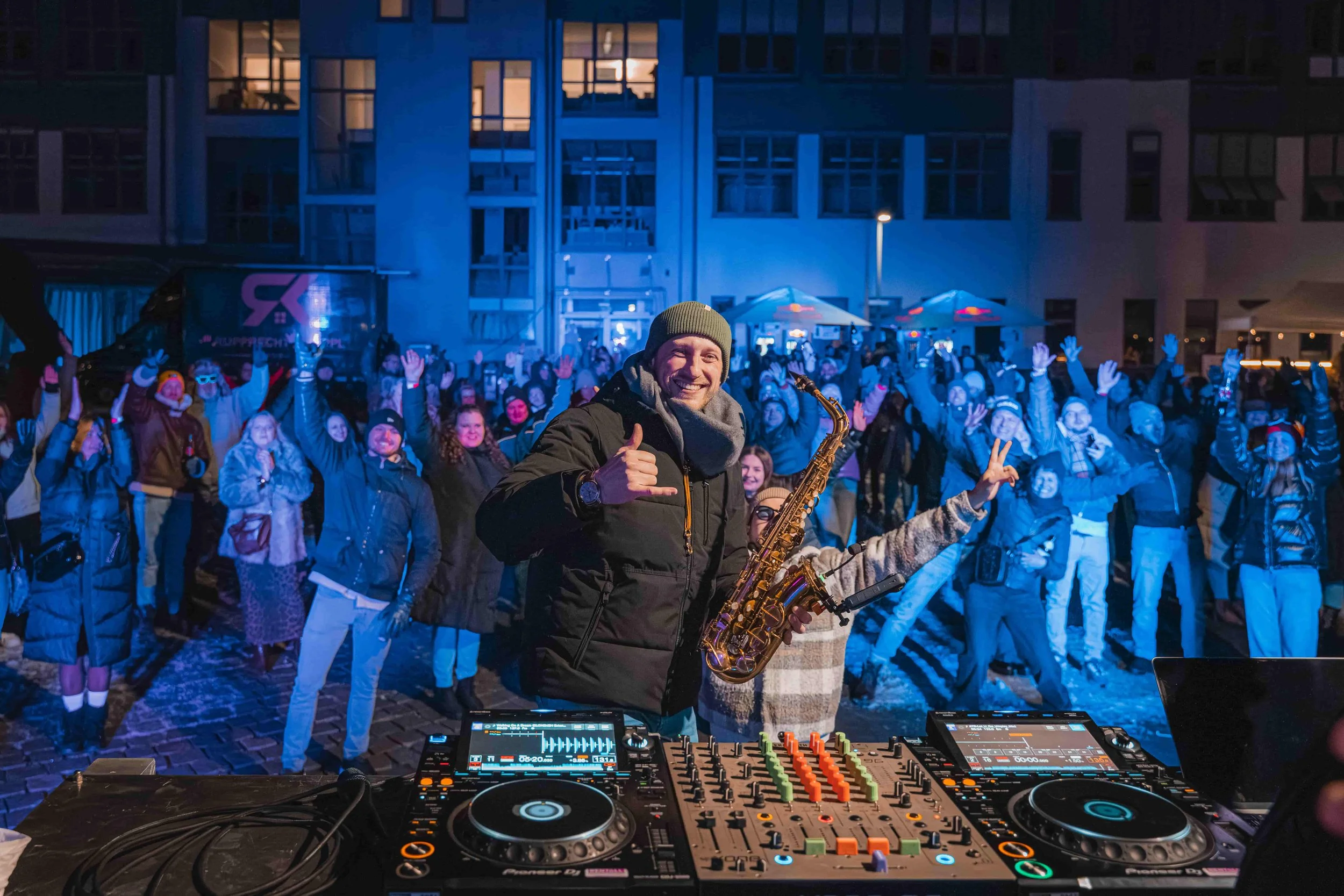 Frederik Heckel vor einem Publikum, das bei einer nächtlichen Veranstaltung im Freien fröhlich tanzt und winkt.