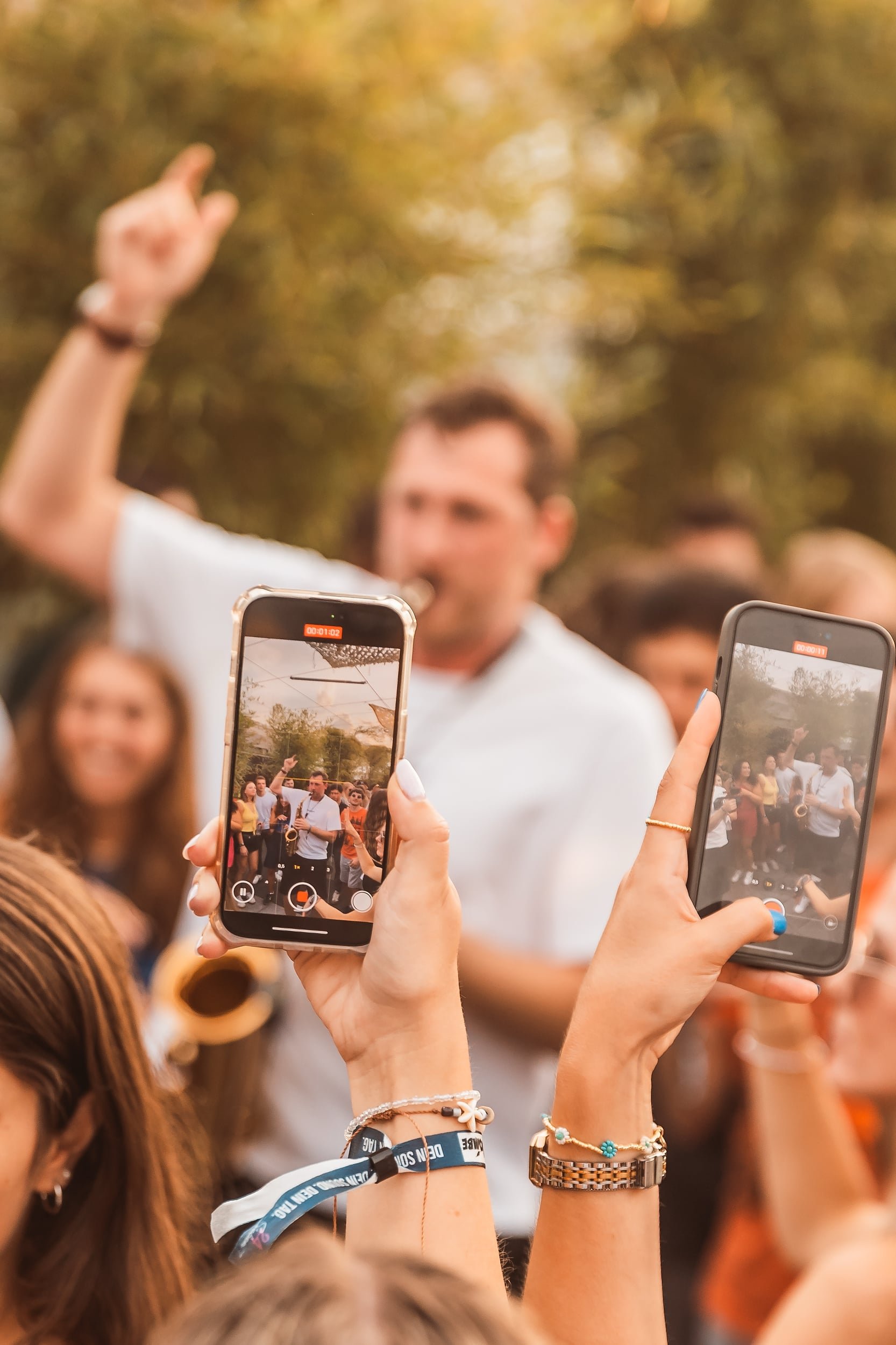 Menschen nehmen Fotos von Frederik Heckel auf, der im Freien auftritt, mit Smartphone-Kameras.
