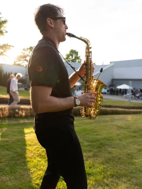 Frederik Heckel spielt Saxophon im Freien bei Sonnenuntergang.