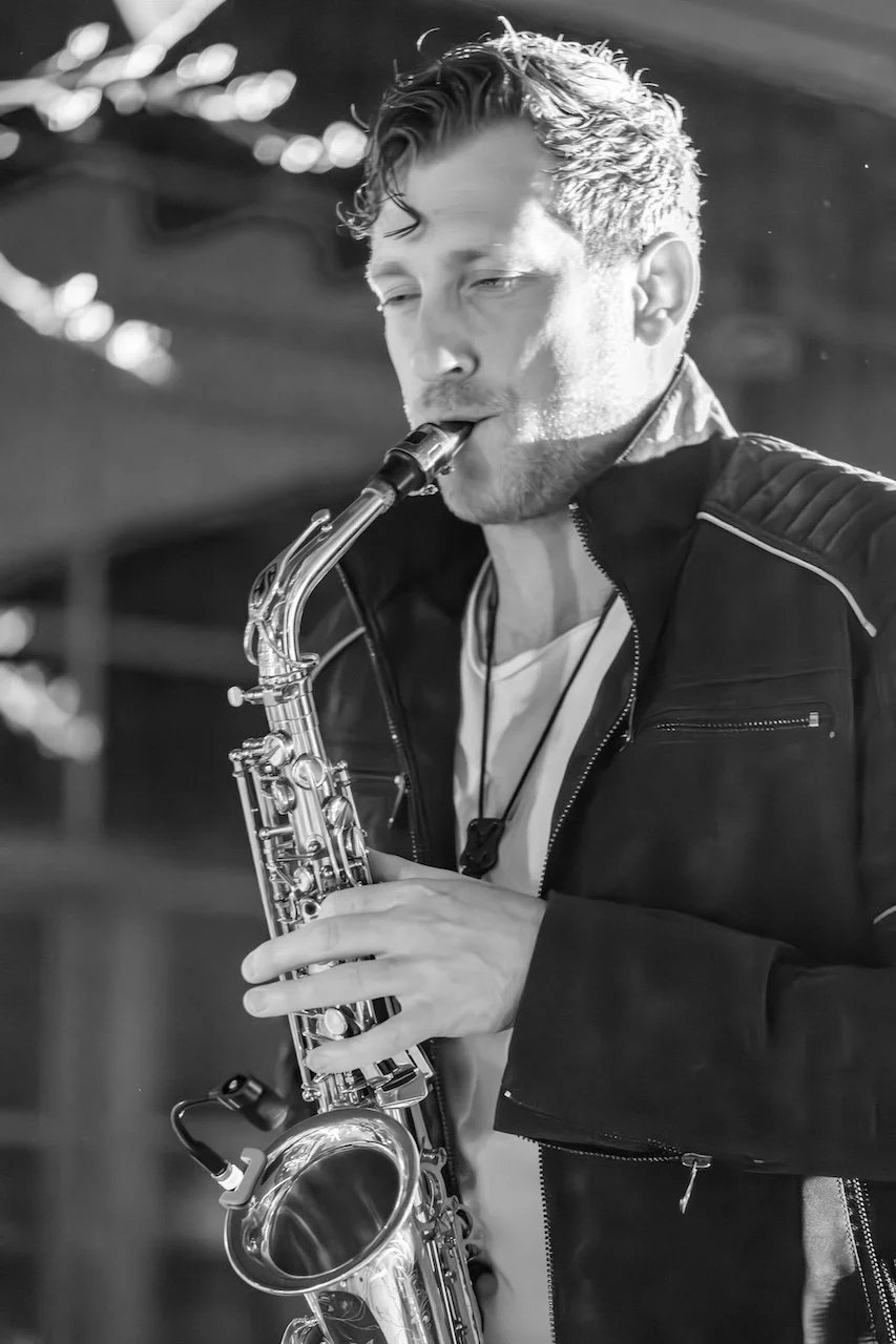 Schwarz-weißer Foto von Frederik Heckel, der auf einer Bühne Saxophon spielt.