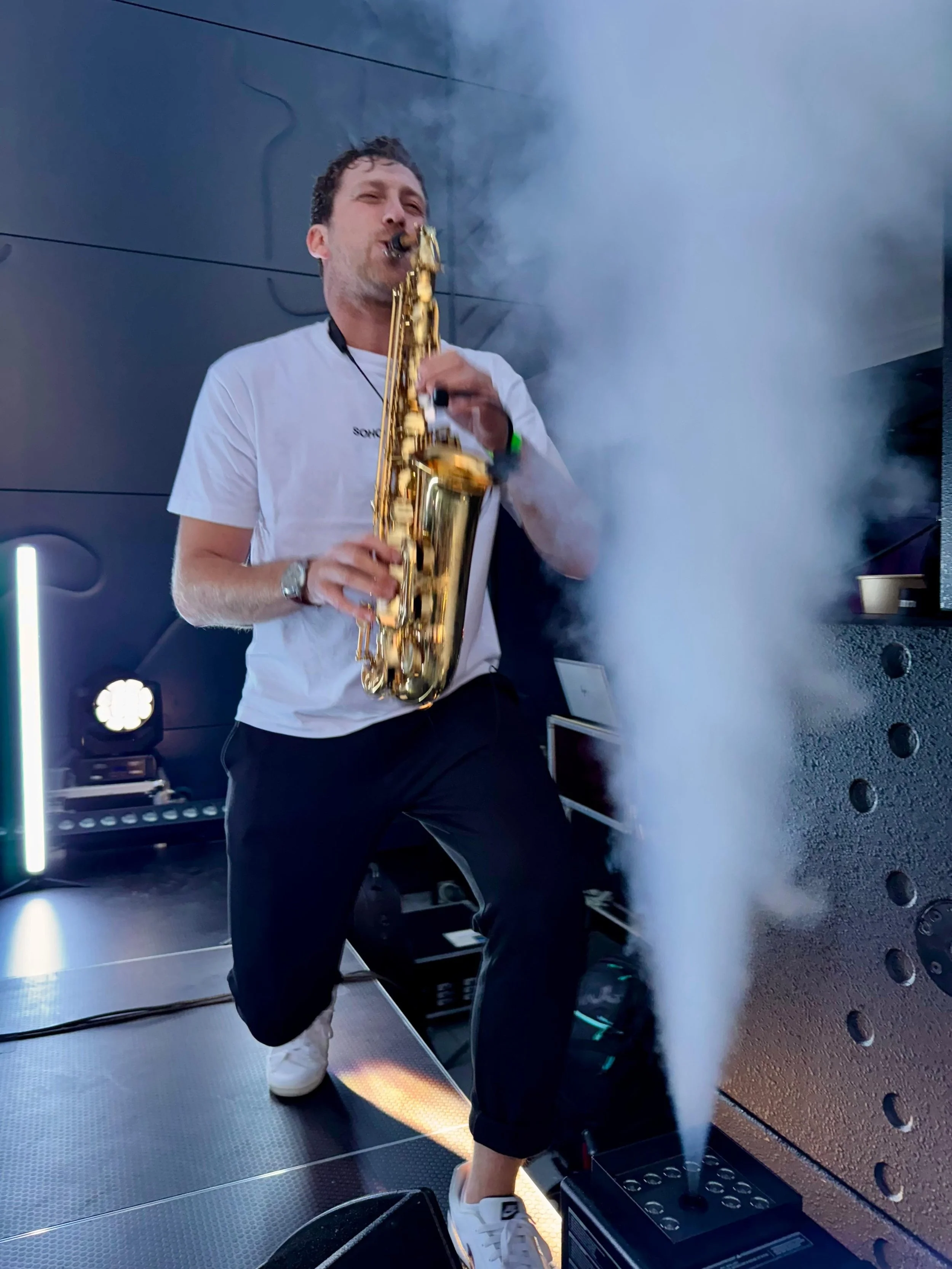 Frederik Heckel spielt auf einem Saxophon, das von Nebel oder Dampf umgeben ist, auf einer Bühne.