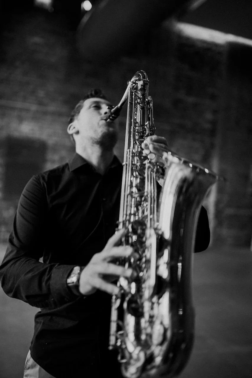 Frederik Heckel spielt auf einem Saxophon, genommen in schwarz-weiß, in einem Raum mit dunklem Hintergrund.