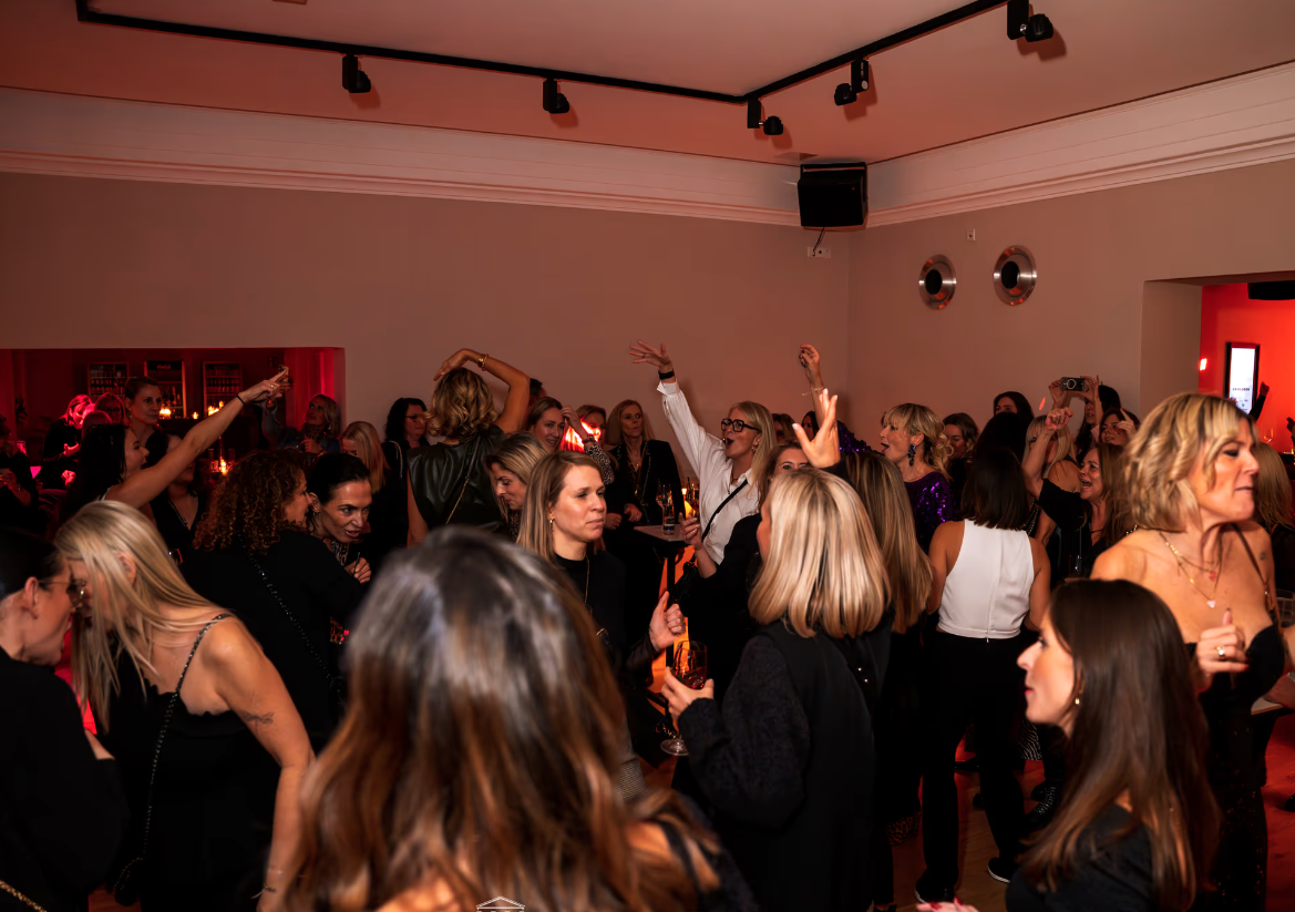 Menschen tanzen und feiern in einer Party- oder Veranstaltungsraum, einige haben ihre Hände in die Luft, während sie zu Musik feiern.