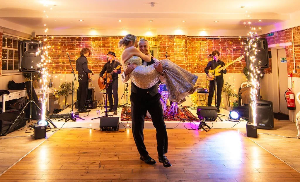 Bride and groom sharing their first dance surrounded by indoor cold spark effects and live band at Sopley Mill wedding reception.