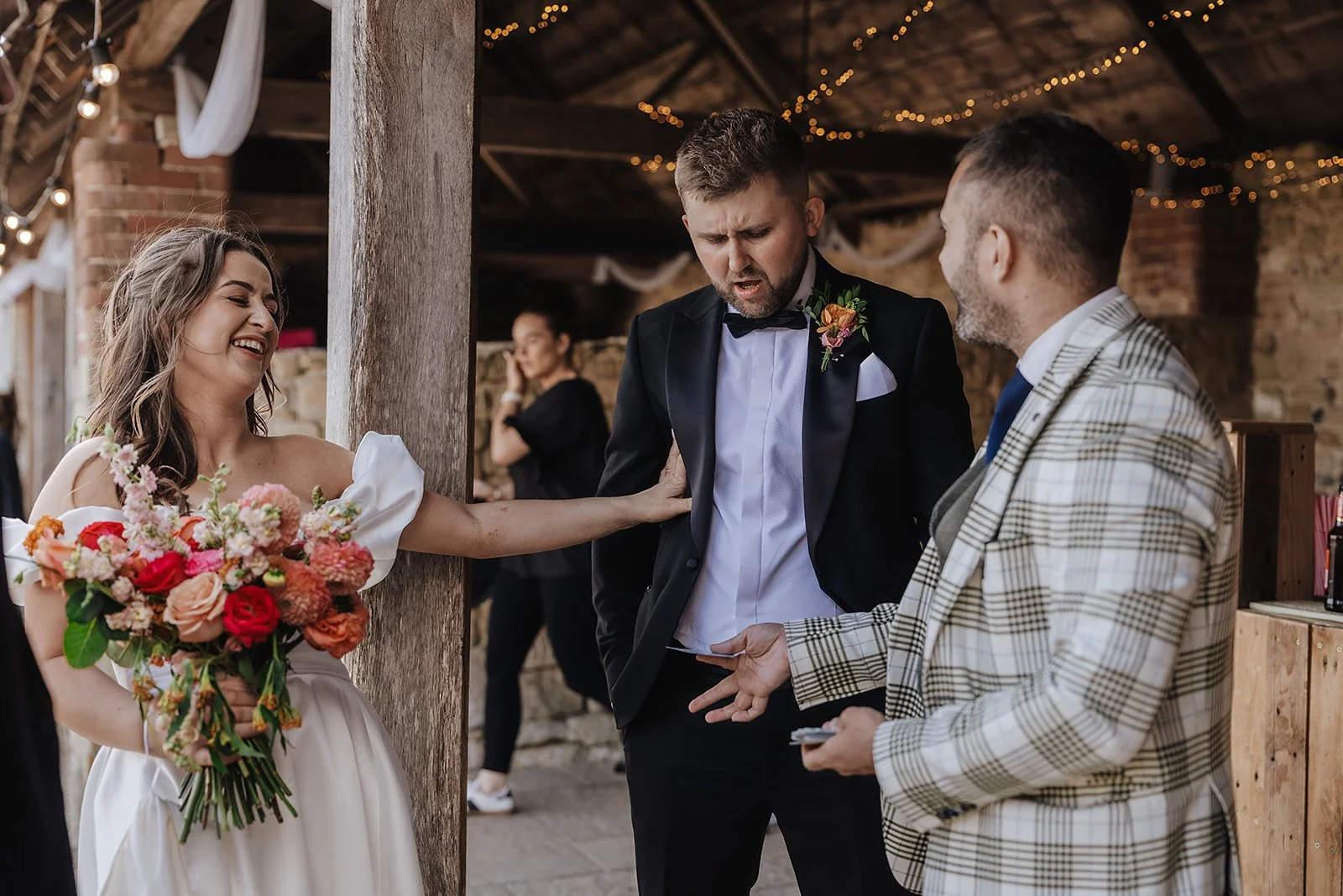 Wedding magician performing close-up magic for a bride and groom in a rustic barn venue