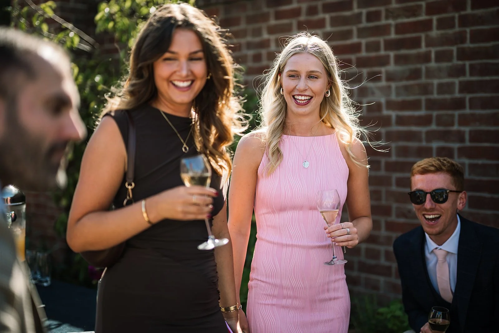 Garden party guests laughing and reacting to a close-up magic performance in a beautiful outdoor setting