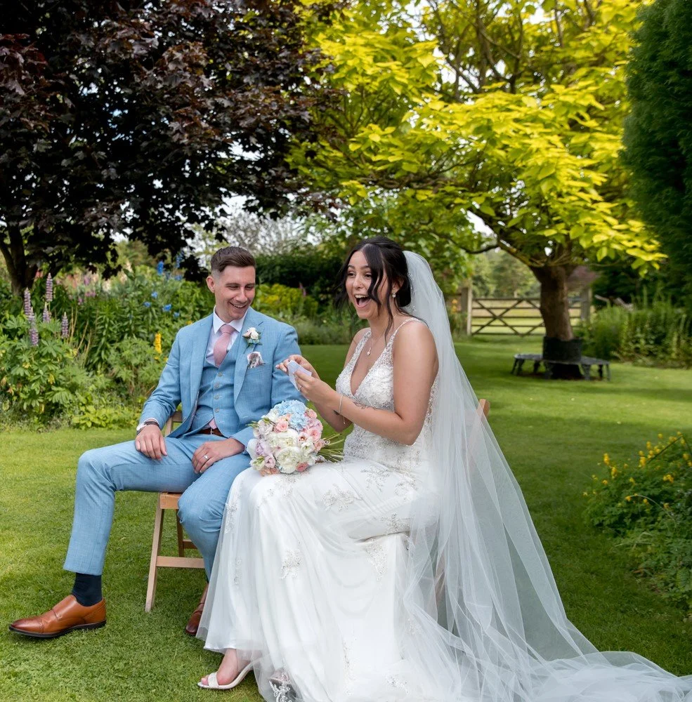 Newlyweds enjoying a magic trick in the gardens at Parley Manor wedding venue in Christchurch, Dorset