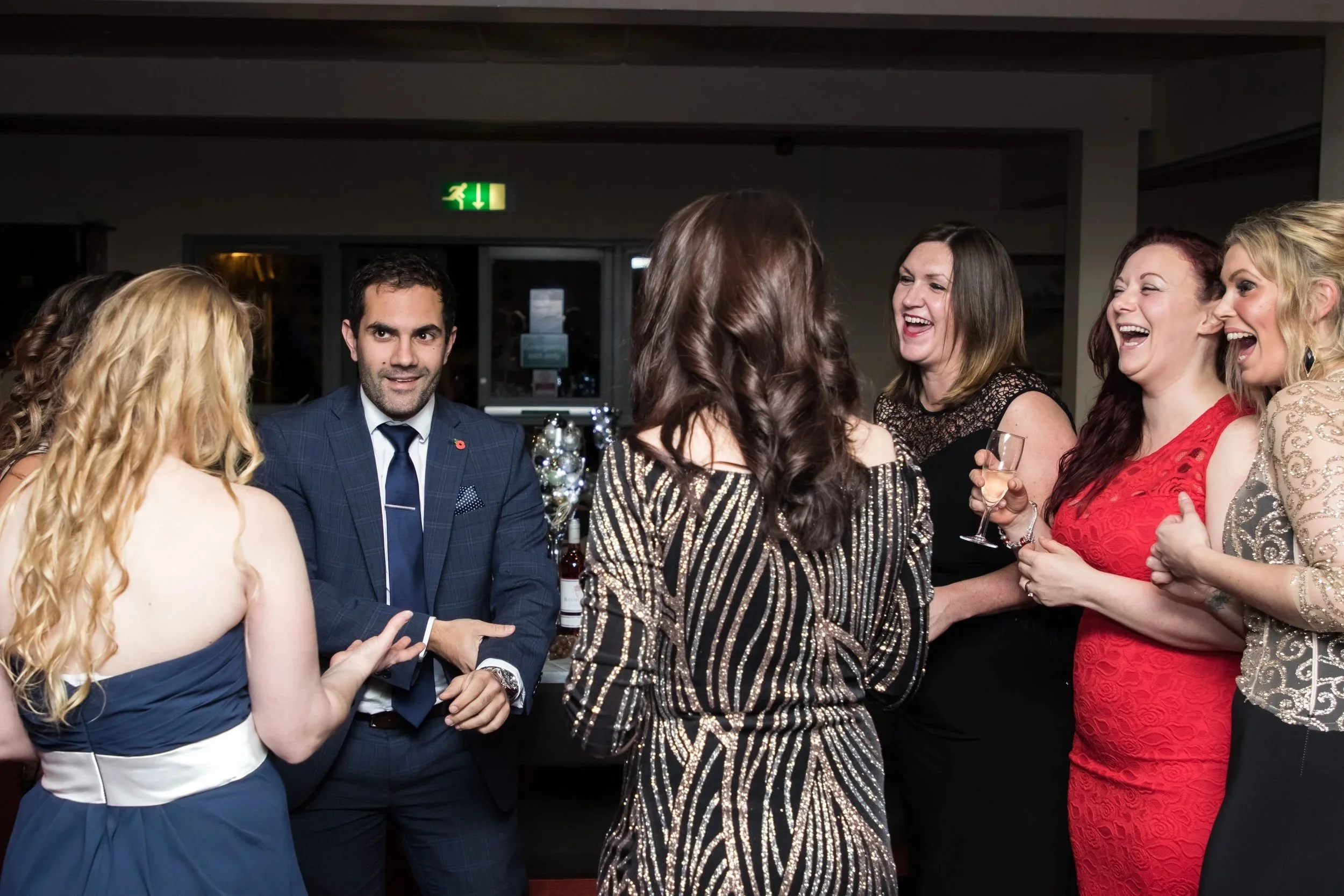 A group of smartly dressed guests laughing and reacting in delight to a close-up entertainer at a corporate event.