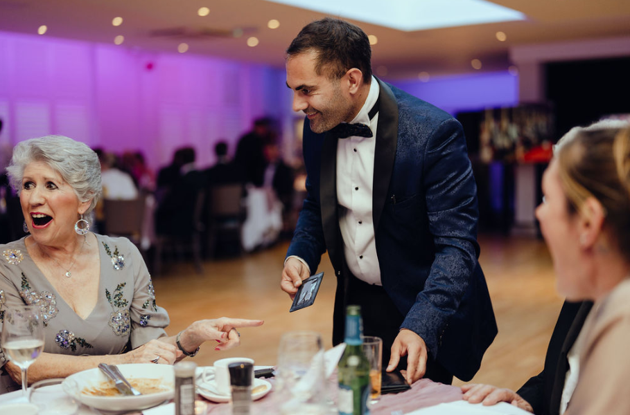 Corporate magician performing close-up magic for smiling guests at a corporate dinner