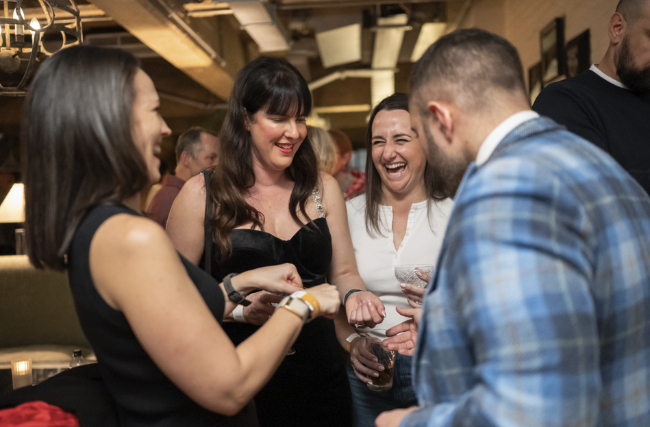Guests laughing and reacting to close-up magic at a corporate networking event