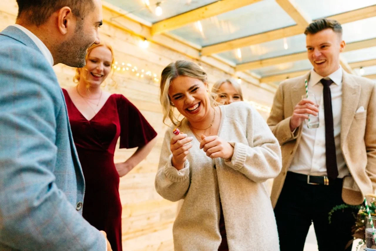 Wedding or event guests reacting with delight to a close-up magician at a Somerset countryside venue