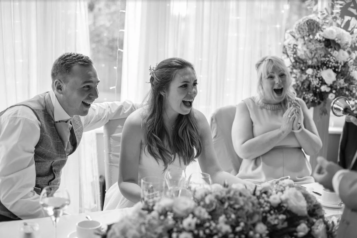 Guests laughing at magic performance  at top table during a wedding breakfast