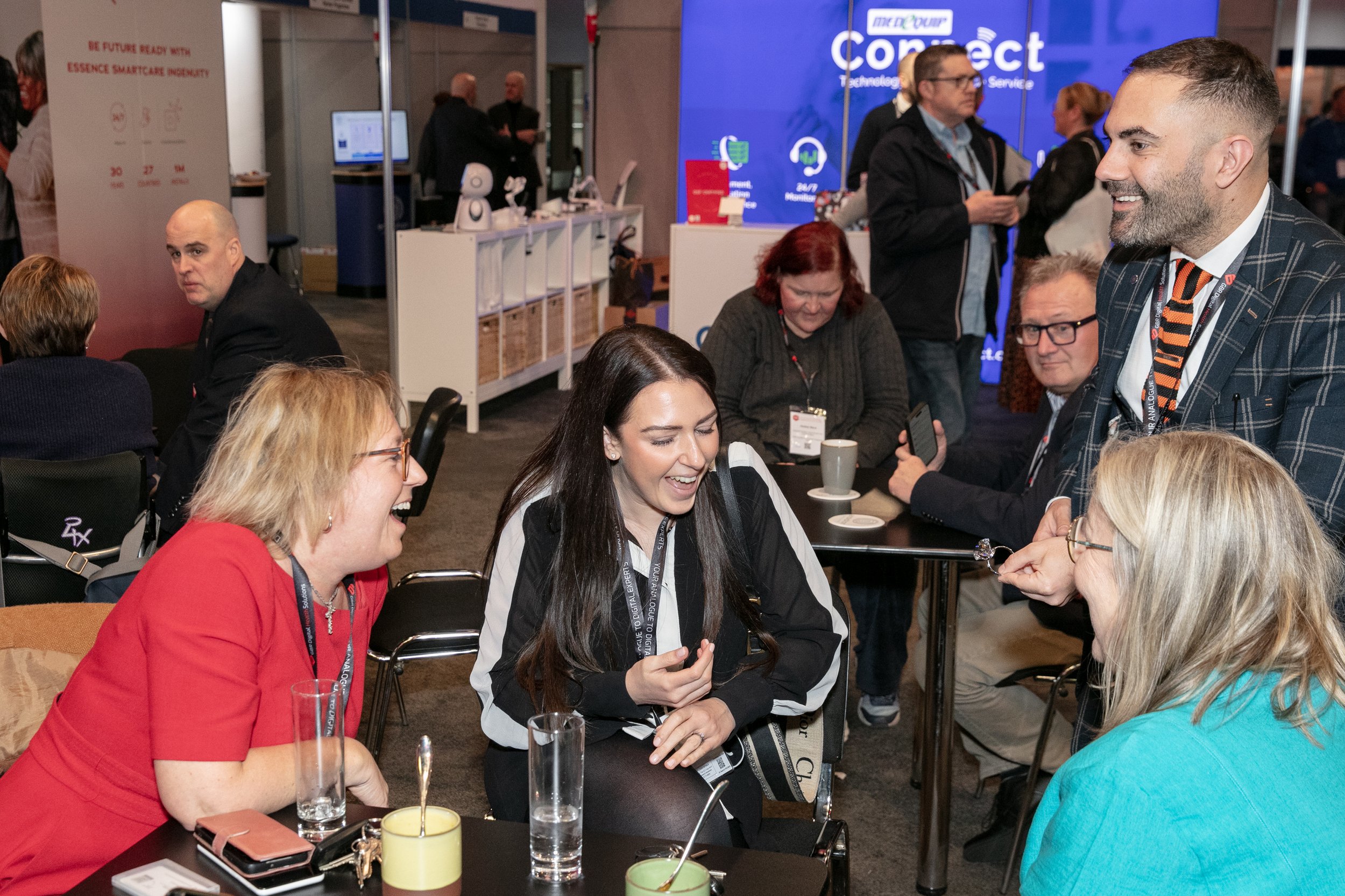 Exhibition magician performing close-up magic for laughing attendees at a trade show