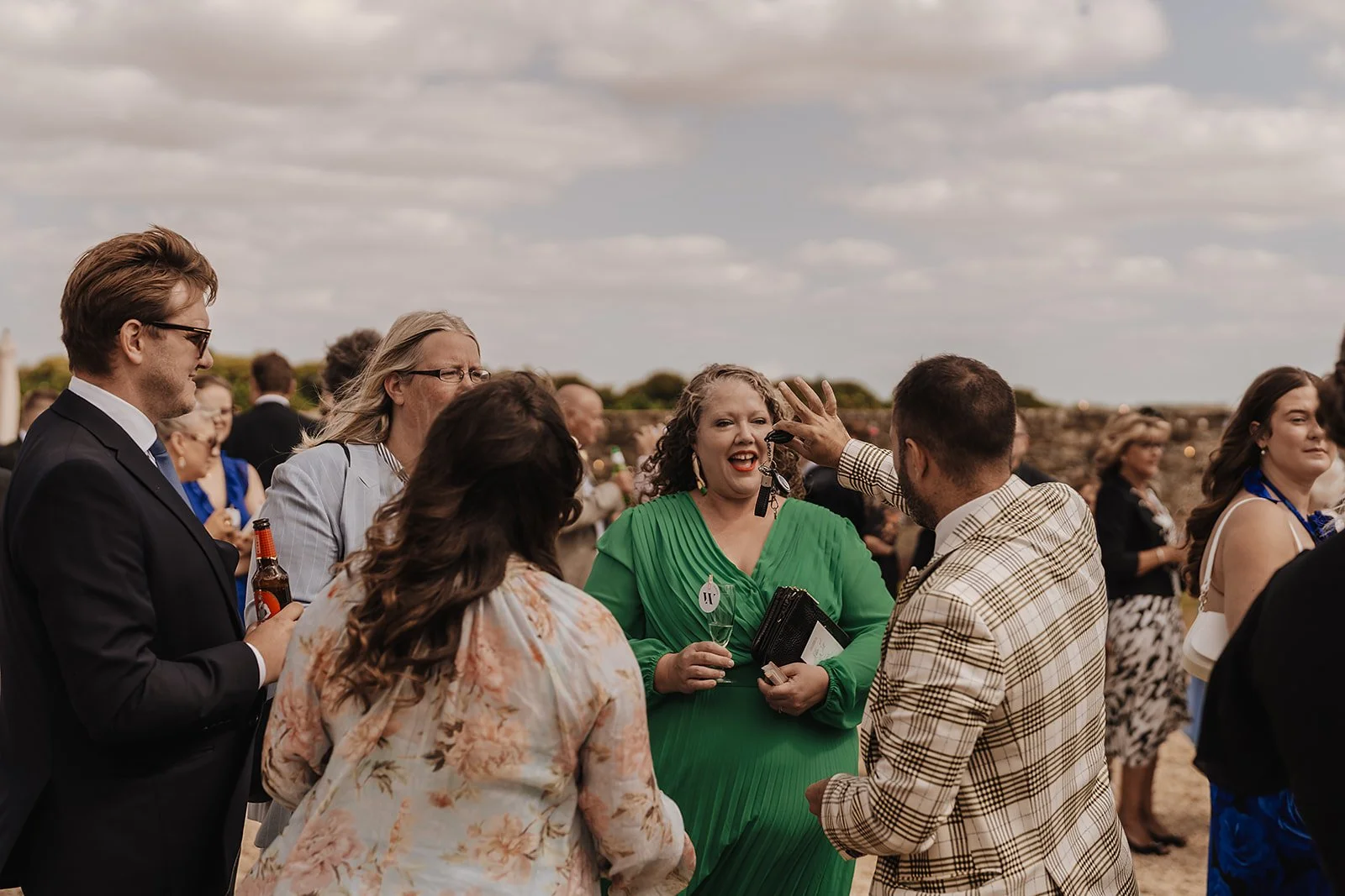 Wedding guests laughing and reacting with delight to entertainment during a drinks reception