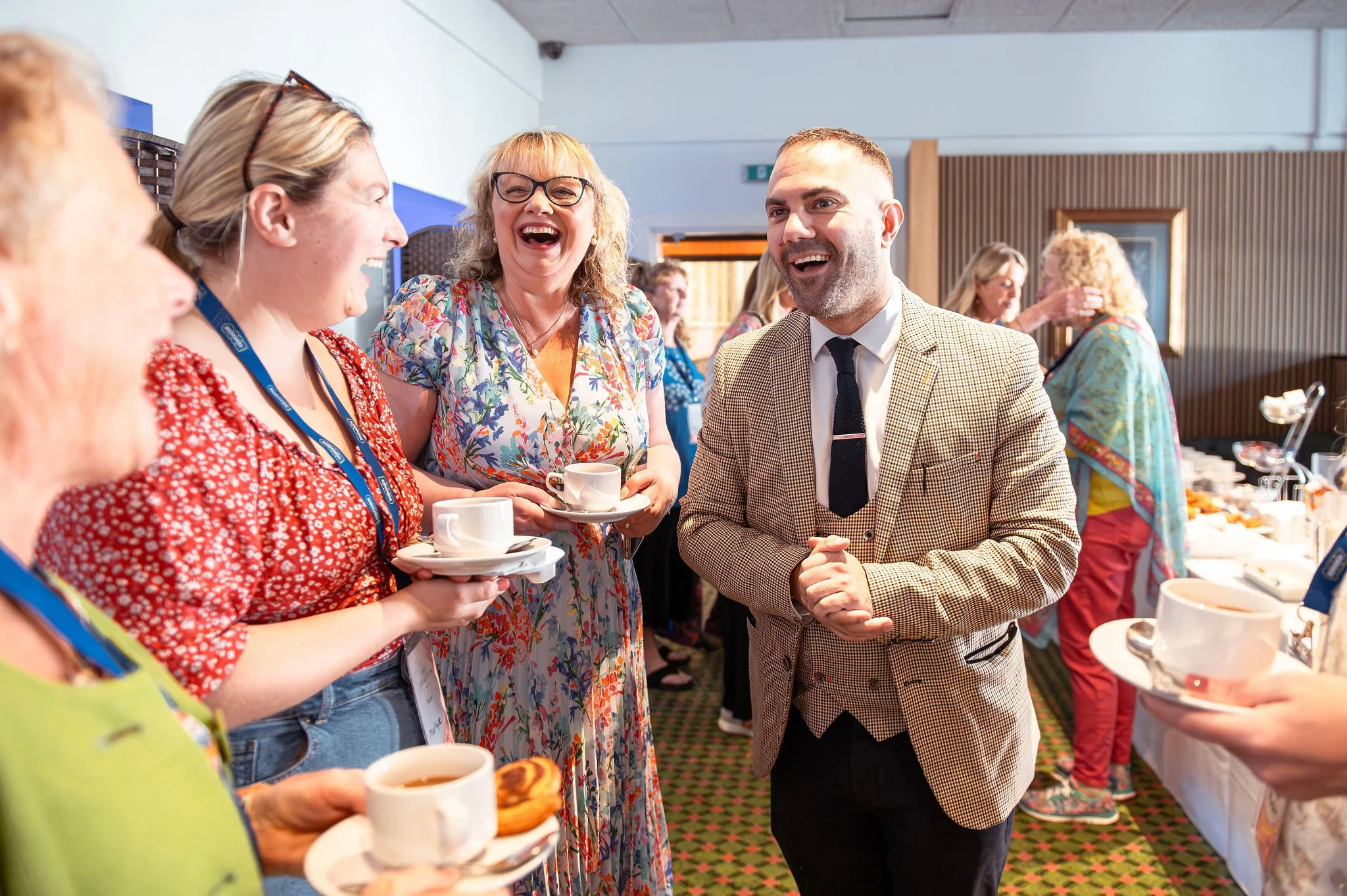 Professional magician performing close-up magic for laughing professionals at a corporate networking event