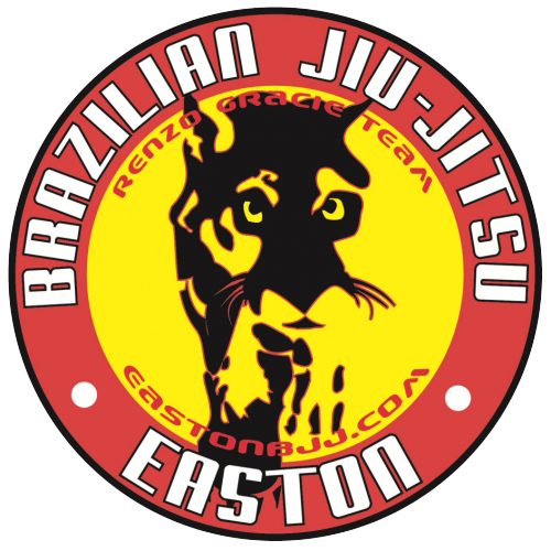 A circular logo with a black outline, featuring a depiction of a jaguar's face in black and yellow in the center. The background is yellow, and the outer ring is red with white text that reads 'BRASILIAN JIU JITSU EASTON'. Inside the yellow circle, there are additional red and yellow words: 'RENZO ORTAGE TEAM' at the top and 'GUSTON BJJ.COM' at the bottom.