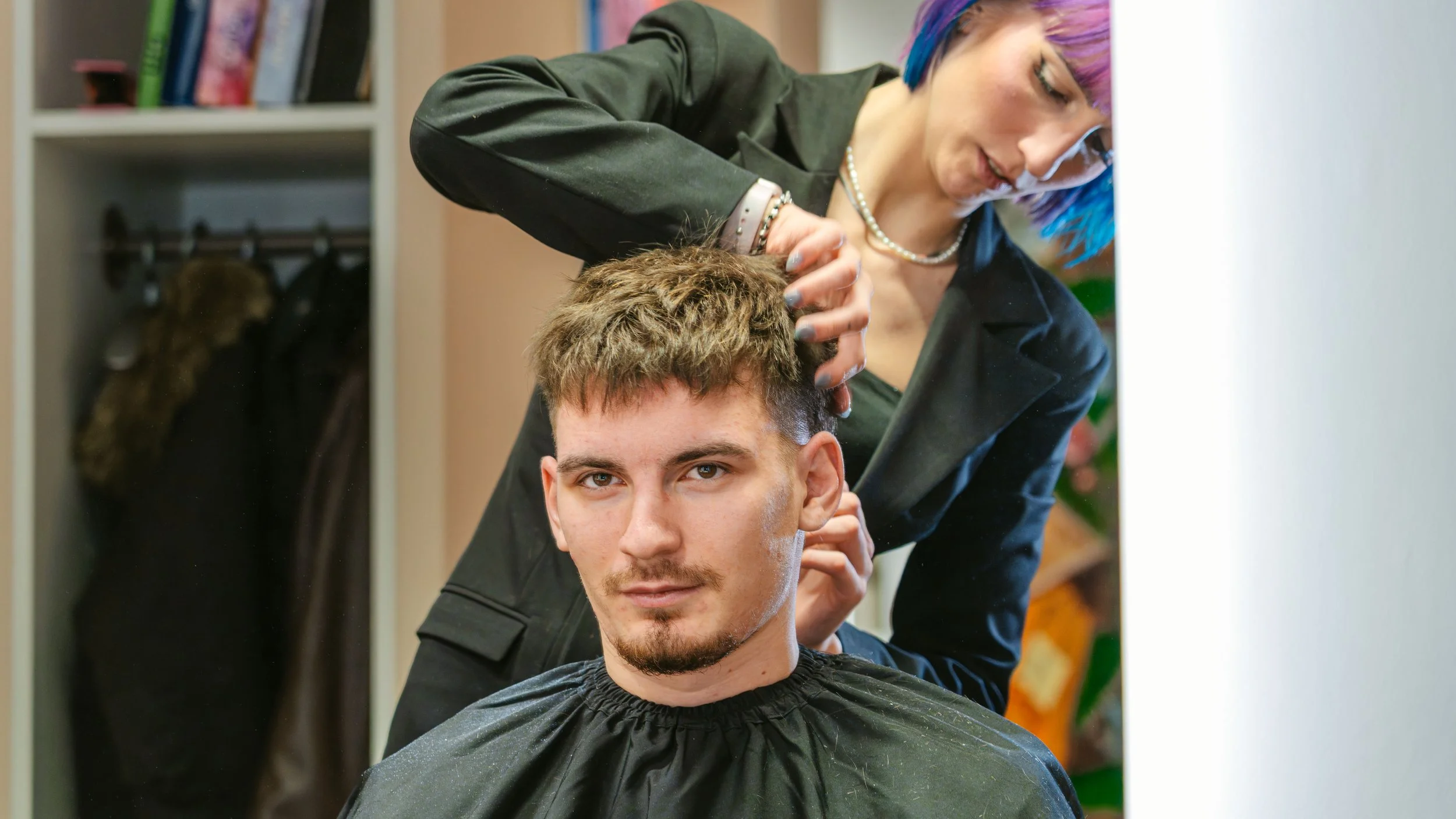 Eine Friseurin schneidet einem Mann die Haare in einem Friseursalon.