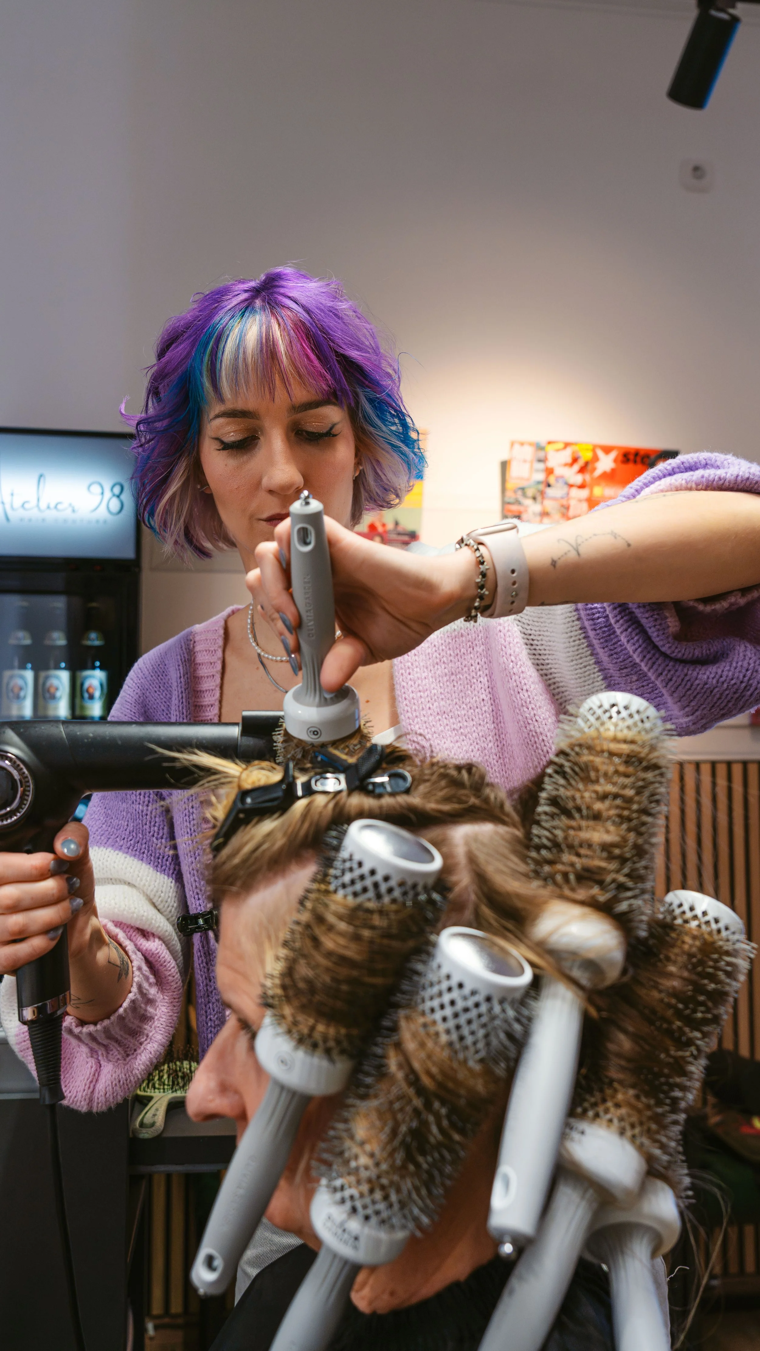 Friseurin stylt eine Kundin mit Lockenwicklern in einem Friseursalon.