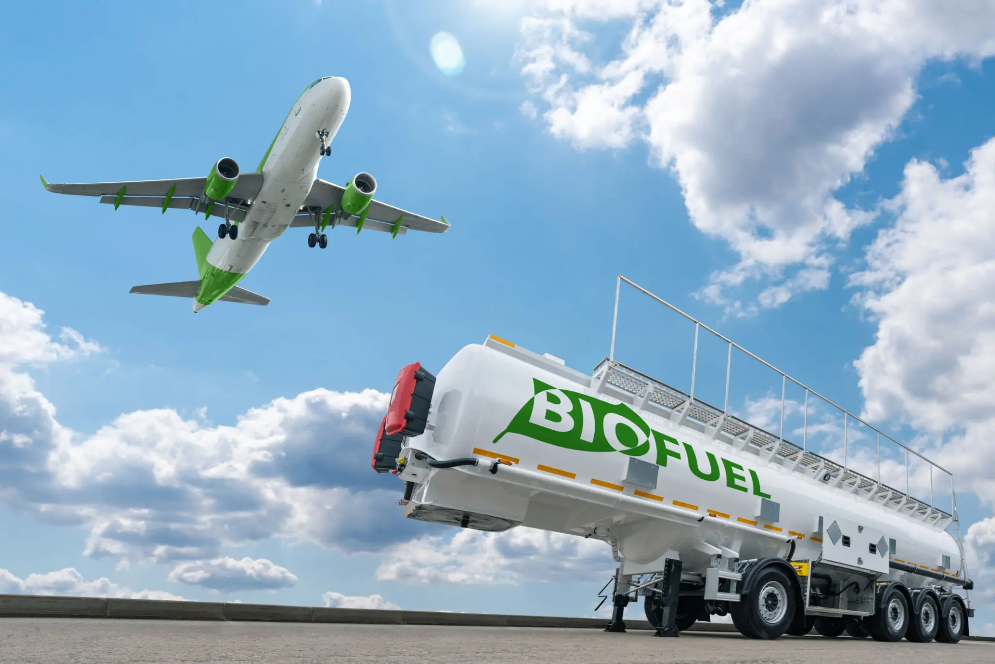 An airplane flying in the sky and a biofuel truck below on the ground.