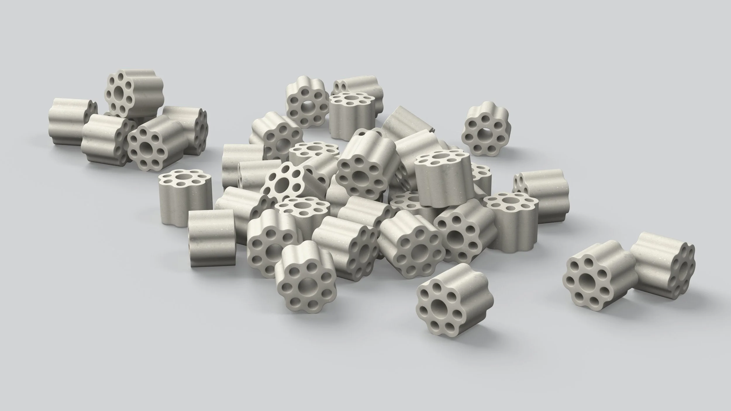 Multiple small cylindrical objects with multiple holes, scattered on a light gray surface.