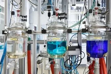 Lab equipment with glass containers filled with different colored liquids in a scientific laboratory.