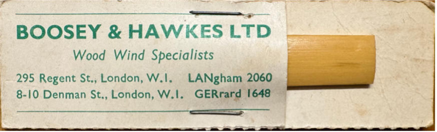 A clarinet reed in a paper sleeve with Boosey & Hawkes LTD printed on to paper