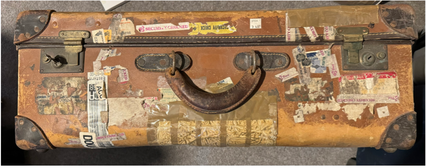 photo of an old brown suitcase will worn and faded travel stickers