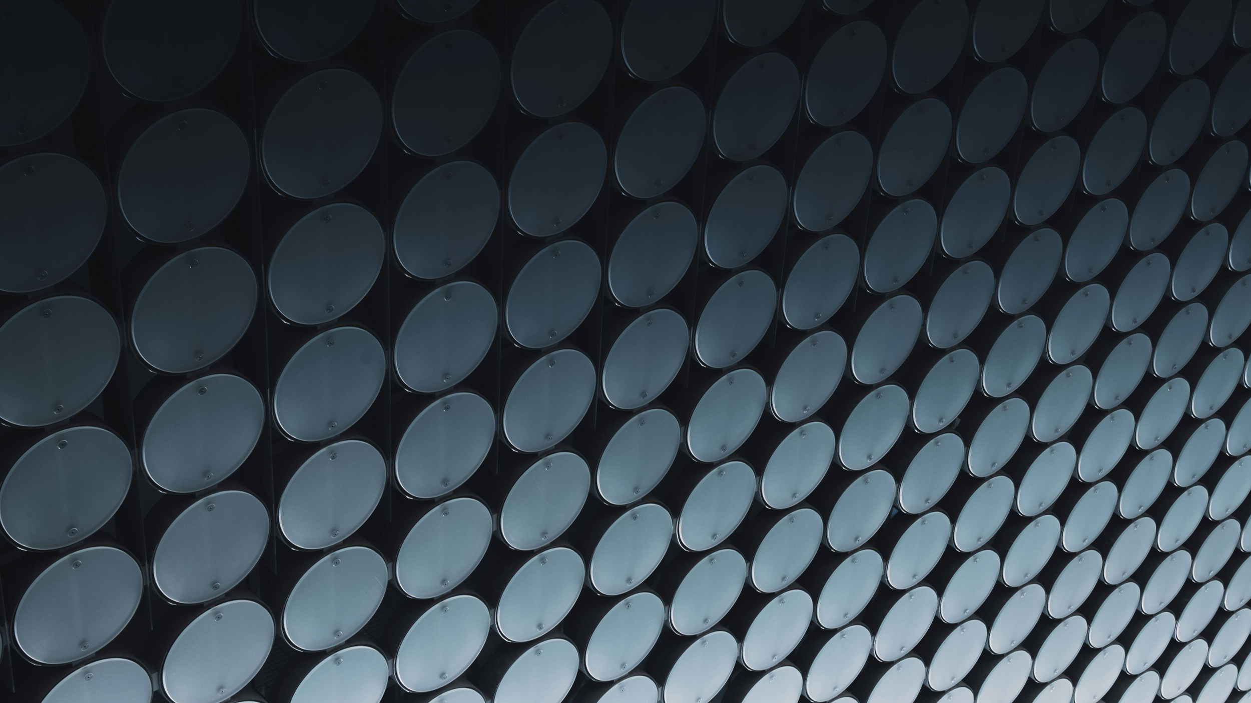 A geometric pattern of black cylindrical pipes or tubes, arranged in a grid with a consistent circular shape and dark tones.