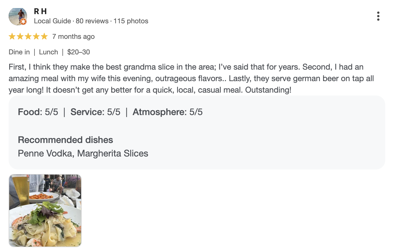 Photograph of a plate of pasta with seafood accompanied by a glass of beer.