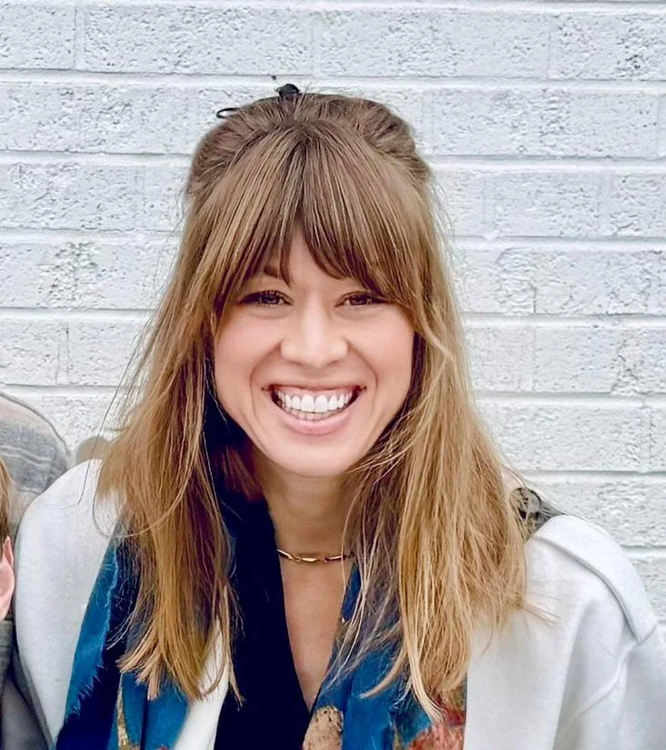 Brook Dieter Kleiman - Volleyball. Woman with long, brown hair smiling in front of a white brick wall.