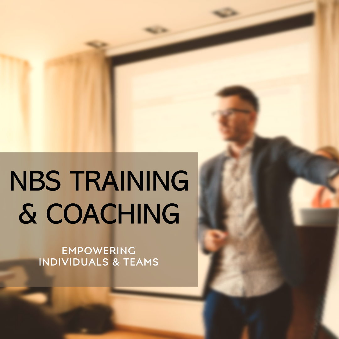 A man giving a presentation in a conference room with a whiteboard and a projection screen, promoting NBS Training & Coaching focused on empowering individuals and teams.