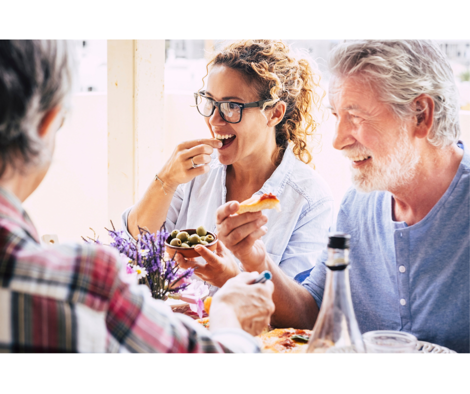 Group of three people sharing a meal and are smiling and happy.