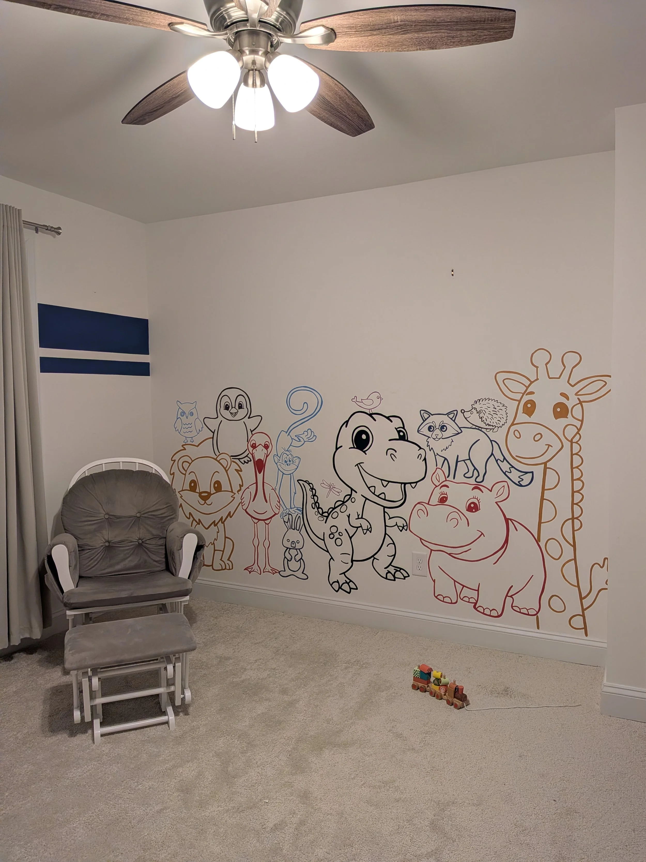 Colorful cartoon animal mural on a white wall in a child's room, featuring lions, giraffes, dinosaurs, and other animals along with whimsical characters.
