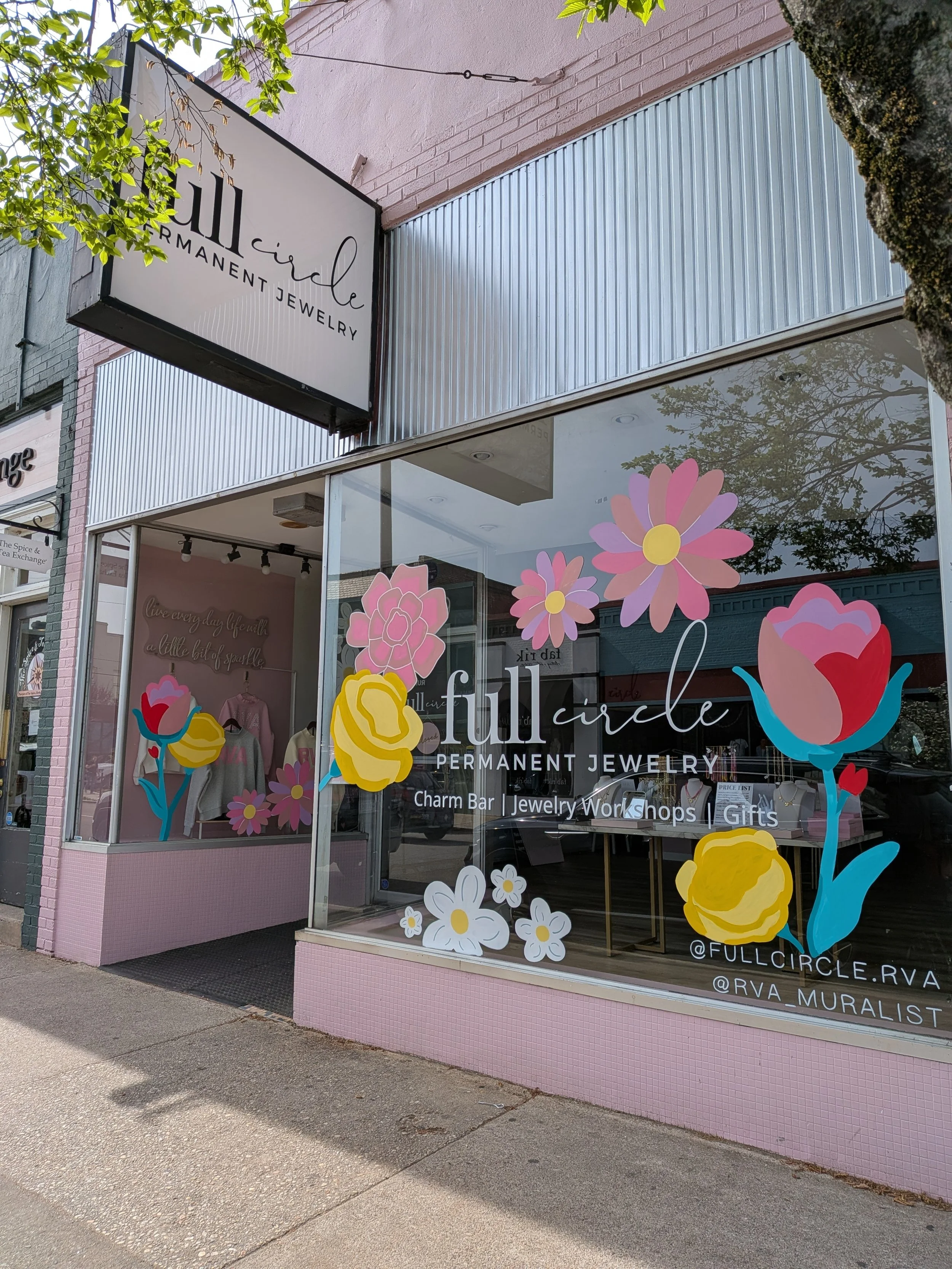 Storefront for Full Circle Permanent Jewelry, with floral window decals including pink, yellow, and red flowers, and a sign displaying the store name and offerings.